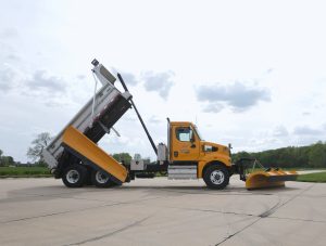 side view photo of truck with rear wing and bed lifted.