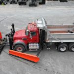 view of the driver side of the Champion, NY truck, the front plow has a salt scraper attachment.